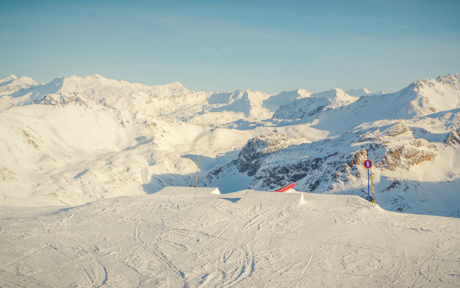 A bright bluebird day over the resort — sunlit snow slopes and clear blue sky